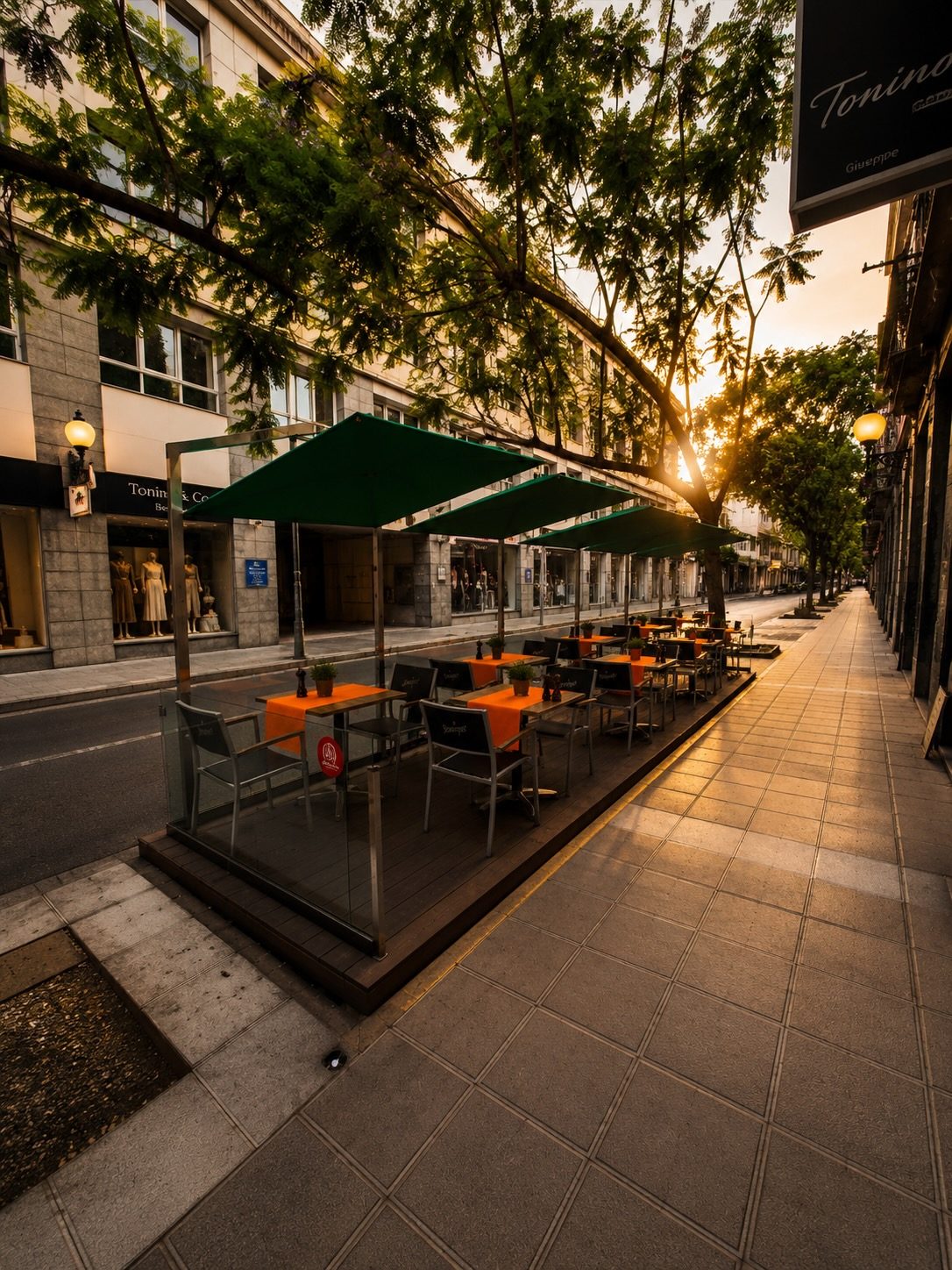 Terraza de Casa Magnolia al atardecer — mesas con manteles naranjas bajo sombrillas verdes